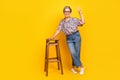 Full size photo of pretty retired female lean on chair show v-sign wear trendy leopard print outfit isolated on yellow Royalty Free Stock Photo