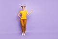 Full size photo of pretty teenager lady holding arm raised indicating finger empty space advertising novelty wear yellow