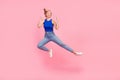 Full size photo of pretty young woman jump fight empty space wear blue top isolated on pink color background Royalty Free Stock Photo
