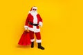 Full size photo of santa claus man wearing red costume celebrate happy new year holding shopping bags isolated on yellow Royalty Free Stock Photo