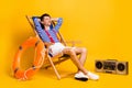 Full size photo of sleepy relaxed young man lie chair nap lifeguard isolated on yellow color background