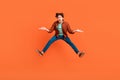 Full size photo of unhappy upset man jumping shrug shoulders wtf hesitant doubt isolated on orange color background