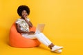 Full size photo of young african excited amazed happy girl woman sit armchair work computer isolated on yellow color Royalty Free Stock Photo