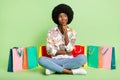 Full size photo of young black girl think thoughtful sit floor shopping bags look empty space over green color