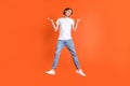 Full size photo of young clueless ignorant man jump up shrug shoulders isolated on orange color background Royalty Free Stock Photo