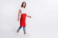 Full size photo of young happy cheerful lovely woman hairdresser go walk in red apron isolated on grey color background Royalty Free Stock Photo