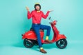 Full size photo of young hesitant man on scooter hold phone shrug shoulders doubtful isolated on teal color background