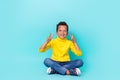 Full size portrait of cheerful positive boy sitting floor demonstrate v-sign isolated on turquoise color background Royalty Free Stock Photo