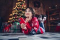 Full size portrait of creative minded girl laying floor use smart phone brainstorming order festive presents tree Royalty Free Stock Photo