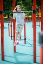 Kid performing the pull-ups on the outdoor fitness equipment