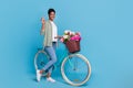 Full size portrait of friendly person demonstrate v-sign stand near bike on blue color background