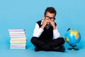 Full size portrait of minded intelligent boy sitting floor look empty space isolated on blue color background Royalty Free Stock Photo