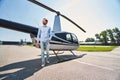 Joyous young man by helicopter at heliport