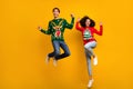 Full size portrait of two delighted overjoyed people jumping raise fists x-mas sale isolated on yellow color background