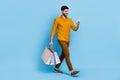 Full size portrait of walking handsome guy use telephone hold packages isolated on blue color background Royalty Free Stock Photo