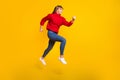 Full size profile photo of blond optimistic lady jump wear red sweater jeans sneakers isolated on bright yellow color Royalty Free Stock Photo