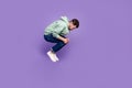 Full size profile photo of falling young man hands hold knees isolated on violet color background Royalty Free Stock Photo