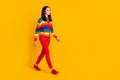 Full size profile photo of nice young woman walking wear rainbow sweater red trousers shoes isolated bright yellow Royalty Free Stock Photo