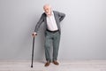 Full size profile photo of old sad man touch back stand with wand wear dark sweater trousers isolated on grey wall