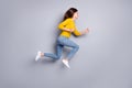 Full size profile photo of optimistic brunette nice lady jump run wear yellow sweater jeans sneakers isolated on grey Royalty Free Stock Photo