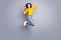 Full size profile photo of optimistic brunette nice lady jump wear yellow sweater jeans sneakers isolated on grey color Royalty Free Stock Photo