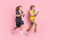 Full size profile photo of optimistic funny couple jump look telephone wear colorful clothes isolated on pastel pink Royalty Free Stock Photo