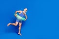 Full size profile side photo of mature smiling man with buoy jumping in pool isolated on blue color background Royalty Free Stock Photo