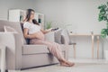 Full size profile side photo of young beautiful happy smiling positive pregnant woman sit sofa watching tv at home house Royalty Free Stock Photo