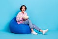 Full size profile side photo of young girl sit beanbag eat pop corn watch film over blue color background