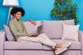 Full size profile side photo of young guy sit couch weekend rest comfort use laptop isolated over blue color background Royalty Free Stock Photo