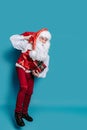 Full size of santa who claus carrying huge bag of presents while holding gift box in hand Royalty Free Stock Photo