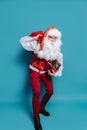 Full size of slinking santa who claus carrying huge bag of presents while holding gift box in hand Royalty Free Stock Photo