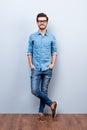 Full size vertical portrait of cheerful brunet young man in casual stylish wear. He looks at camera on lifgt background