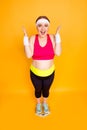 Full-size vertical portrait of enthusiastic cheerful amazed pop-eyed fatty girl standing on digital bathroom scales and Royalty Free Stock Photo