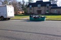 Full soft sided green dumpster bag on the side of a residential street in front of a house undergoing renovation