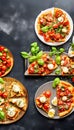 Full table of italian meals on plates Pizza, pasta, ravioli, carpaccio. caprese salad and tomato bruschetta on black background. Royalty Free Stock Photo