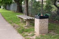 Full trash can next to empty bench Royalty Free Stock Photo