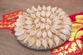 A full tray of freshly kneaded dumplings is placed on the red envelopes and spring couplets