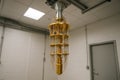 Full view of hanging quantum computer dilution refrigerator inside laboratory, featuring golden cooling structures and cable Royalty Free Stock Photo