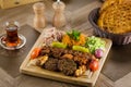 Full view of Persian Mix Kebab of minced meat and chicken With Rice and french fries and vegetables in a large traditional tray on