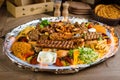 Full view of Persian Mix Kebab of minced meat and chicken With Rice and french fries and vegetables in a large traditional tray on