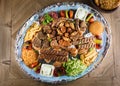 Full view of Persian Mix Kebab of minced meat and chicken With Rice and french fries and vegetables in a large traditional tray on