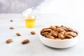 A full white bowl of peeled almonds sits on a light gray concrete surface. A small jar of honey stands in the background. Royalty Free Stock Photo