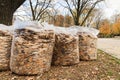 Full white garbage bags with autumn leaves on the ground in the city park. Seasonal cleaning of foliage Royalty Free Stock Photo