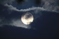 Full white moon behind clouds