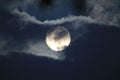 Full white moon behind clouds