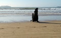 A fully covered Muslim woman in black niqab and abaya walking with her little son on the beach Royalty Free Stock Photo