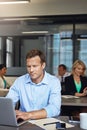 Fully engaged in his work tasks. a businessman using a laptop at his desk with his colleagues in the background. Royalty Free Stock Photo