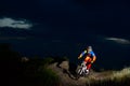 Fully Equipped Professional Downhill Cyclist Riding the Bike on the Night Rocky Trail Royalty Free Stock Photo