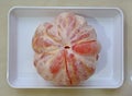 A fully peeled pomelo on a white rectagular plate